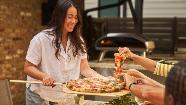 person holding pizza peel with pizza 